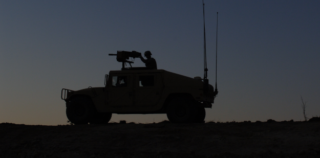 Soldier in humvee against desert sunset
