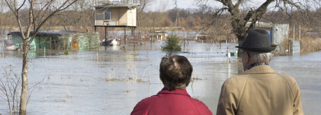 woman and man looking out over flooded houses and road