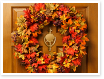This is an image of a wreath of fall leaves on the door of a home.