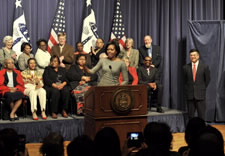 Obamas on podium with Commerce employees behind and Locke looking on ffrom the right. Click for larger image.