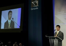 Image of Locke on podium with large-screen image to the left. Click for larger image.
