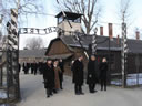 Attorney General Holder, accompanied by the Auschwitz-Birkenau Memorial and State Museum Director Piotr Cywinski, walk under the infamous entrance to the Auschwitz I concentration camp.