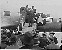 Thumbnail for: Photograph of President Truman waving from the steps leading to the door of his airplane at Washington's National Airport, preparing to take off for a Christmas trip home to Independence, Missouri, with his Military Aide, General Harry Vaughan, and an unidentified woman on the steps behind him., 12/25/1945