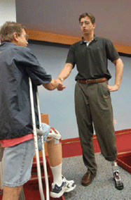 Garth Stewart (right), wearing the new bionic ankle showcased at the Providence VA on July 23, greets a fellow veteran.