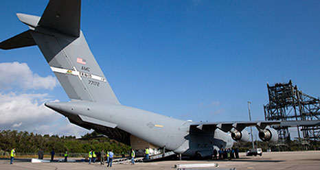 A container with the TDRS satellite is unloaded from a C-17 aircraft.