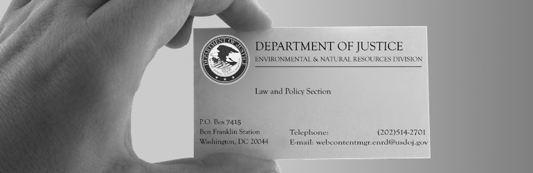 A hand displays a business card with the phone number and address for the Environment and Natual Resources Division.  DOJ/ENRD.