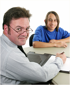 Photograph of a young man talking with an adult.