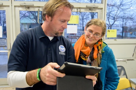 Disability Integration Advisor demonstrates iPad with accessibility features to disaster recovery center worker.