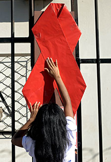 Young woman hangs large AIDS ribbon.