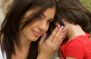 Mother listens to daughter tell a secret in her ear