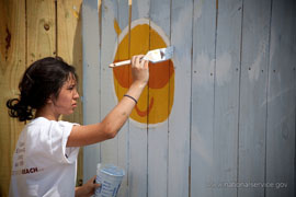 A young woman paints a mural. Photograph courtesy of Corporation for National &Community Service.