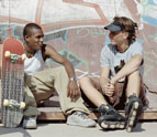 Two young people sit in a skate park talking.