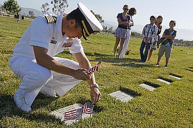 Capt. Jay Kadowaki, commanding officer of Naval Surface Warfare Center (NSWC), Corona Division, places flags at the grave of his uncle, U.S. Army Spc. Robert Kadowaki, who served during the Vietnam War, before speaking at the 32nd annual Memorial Day observance at Riverside National Cemetery. Kadowaki reflected on the cost of freedom and the ultimate sacrifice paid by those driven to serve by love of country and sense of duty.  U.S. Navy photo by Greg Vojtko (Released)  110530-N-HW977-025