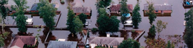 July 2nd, 1994. An aerial view of a flooded neighborhood shows water reaching the second story of some homes. Cars and mailboxes are completely flooded.