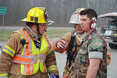 Firefighters from Navy Regional Fire Rescue, Peninsula District, and York County Fire and Life Safety escort Aviation Boatswain's Mate (Handling) 3rd Class Michael Bailey, with a simulated injuring, into a waiting ambulance during Exercise Solid Curtain and Citadel Shield at Naval Weapons Station Yorktown. The exercise is designed to enhance Navy personnel's training and readiness to prepare for and respond to terrorist threats.  U.S. Navy photo by Mark O. Piggott (Released)  120320-N-PK884-004