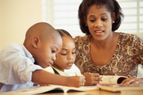 Mother watching children coloring in book with crayons