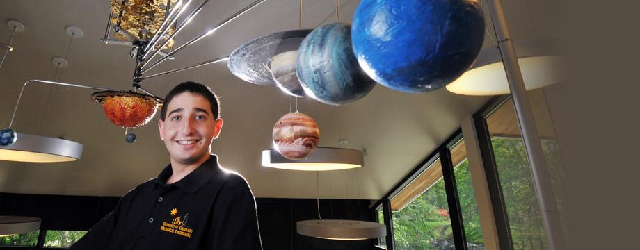 Student is standing in front of the Orrery model. 