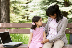 Mother talks to girl on a bench.