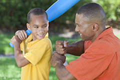 Father teaches boy how to hold a baseball bat correctly.