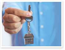 This is an image of a persons hand holding a key with a house-shaped, key-ring attached