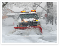 Image of a snow plow on a street during a snow storm.