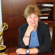 A woman sitting at a desk, next to an academy award.