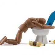 An ill doll on a toilet vomiting.