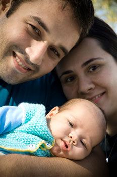 Photograph of young parents holding a baby.