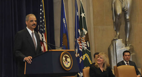 Attorney General Eric Holder speaking at the Department’s Sunshine Week event on March 15, 2010, as OIP Director Melanie Pustay looks on.