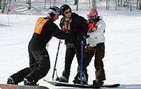 Photograph of a disabled veteran being readied on a snowboard