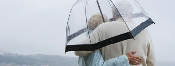 Photo: Older couple secure under umbrella in the rain