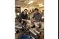 Photo of researchers kneeling behind a dilution refrigerator equipped for microwave measurements.