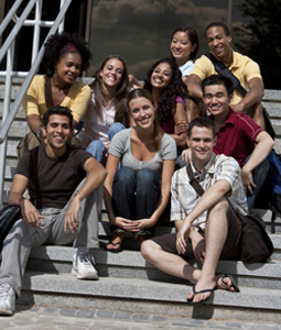 Photograph of a diverse group of young people sitting on the front steps of a building.