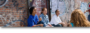 A group of youth sitting in front of a graffitied wall