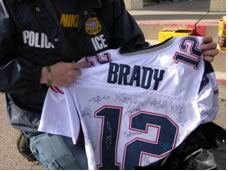 ICE enforcer holding up a football jersey with the name Brady on it.