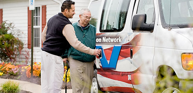 Man helping a Veteran into a van