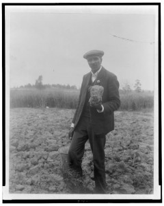 [George Washington Carver, full-length portrait, standing in field, probably at Tuskegee, holding piece of soil]. Photo by Frances B. Johnston, 1906. http://hdl.loc.gov/loc.pnp/cph.3c14302 