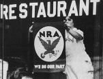 Photograph of a Woman Hanging an NRA Poster in the Window of a Restaurant. Franklin D. Roosevelt Library, ca. 1934.