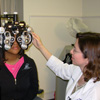 An eye care professional uses a phoropter to detect refractive errors in a teenage patient.
