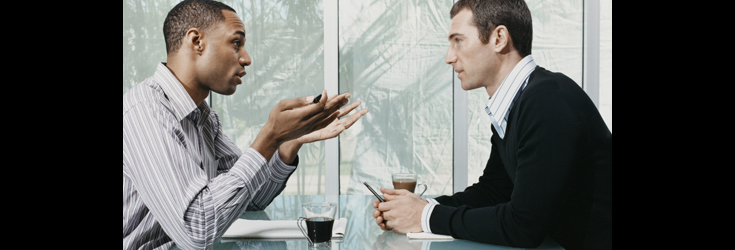 A photo of 2 men sitting across from each other.