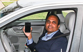 Photo of researcher Ram Dantu holding smart phone in his car.