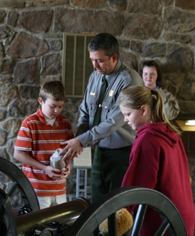 Students on a field trip learn how to load a cannon.