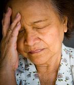 A woman holds her head in pain.