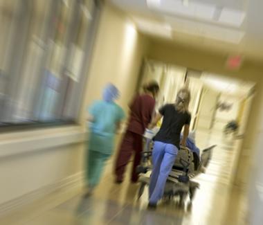 Nurses bringing patient down hospital hall  
