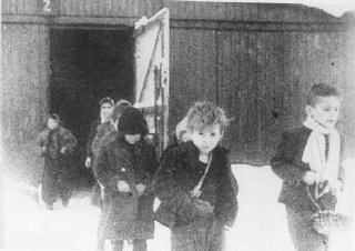 آزادی کے فوری بعد آشوٹز کیمپ کے زندہ بچ جانے والے بچے بیرکوں سے باہر آرہے ہیں۔ پولینڈ، 27 جنوری 1945 کے بعد۔