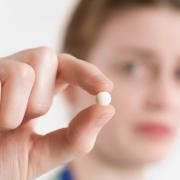 Here is an image of a girl holding a pill.