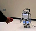 Image of a metal robot named Morphy following a ball held by a researcher.