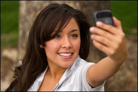 Photo of a Native American woman taking a photo with a cellphone.