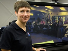 Picture of DLN Educator Rachel Powers with a webcast with a class displayed on a television screen behind her