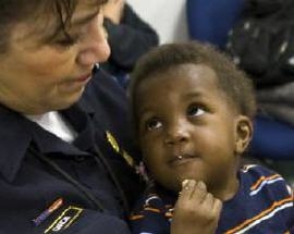 Haitian child eating and looking at a DHS Customs and Border Patrol officer